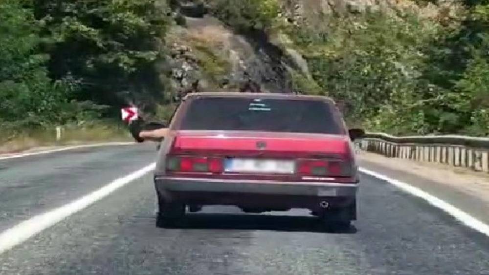 Ayaklarını camdan sarkıtarak trafiği tehlikeye attı
